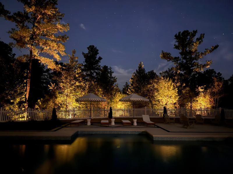 Patio, Pool & Backyard Lighting project — Pool, umbrellas, golden uplit tree line