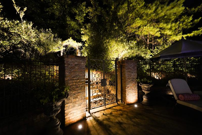 Step, Stair & Hardscape Lighting project — Iron garden gate between lit brick columns (pro shot)