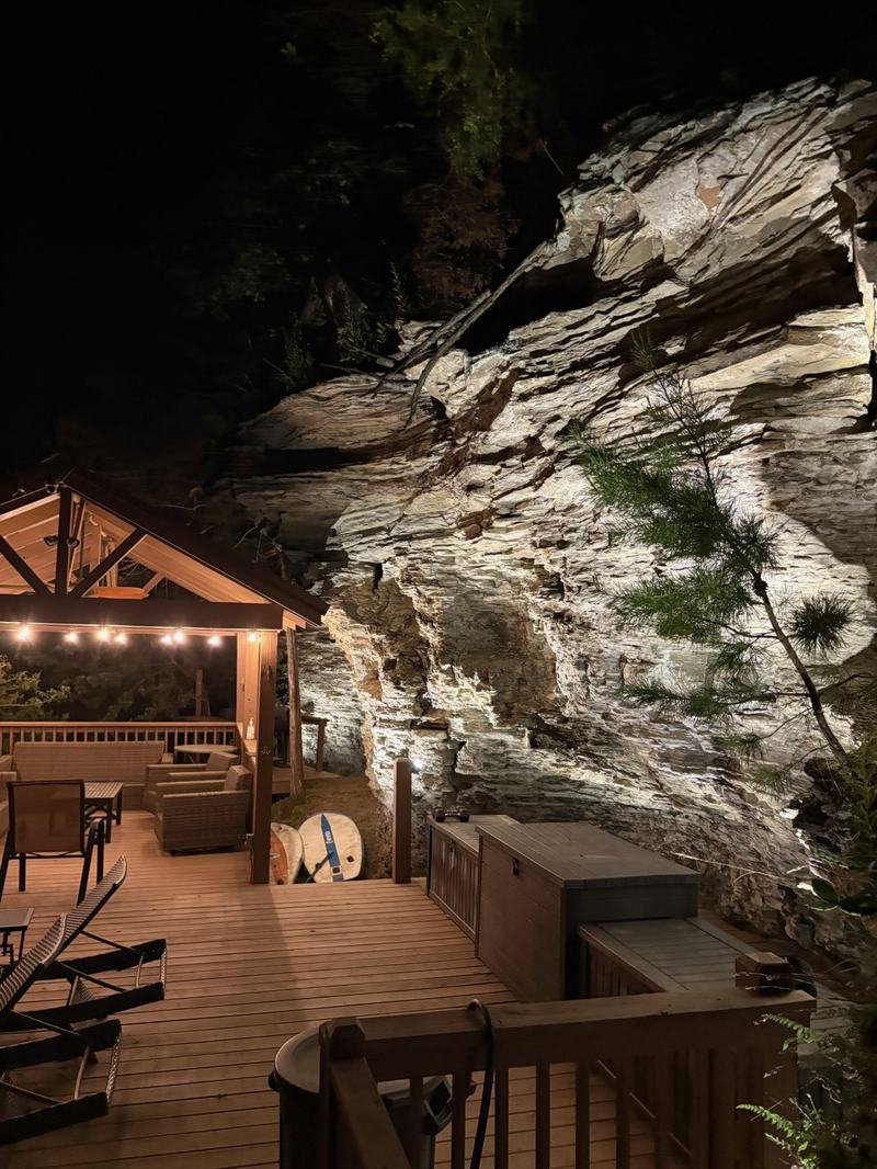 Patio, Pool & Backyard Lighting project — Lakeside deck, uplit rock bluff + string-lit pavilion