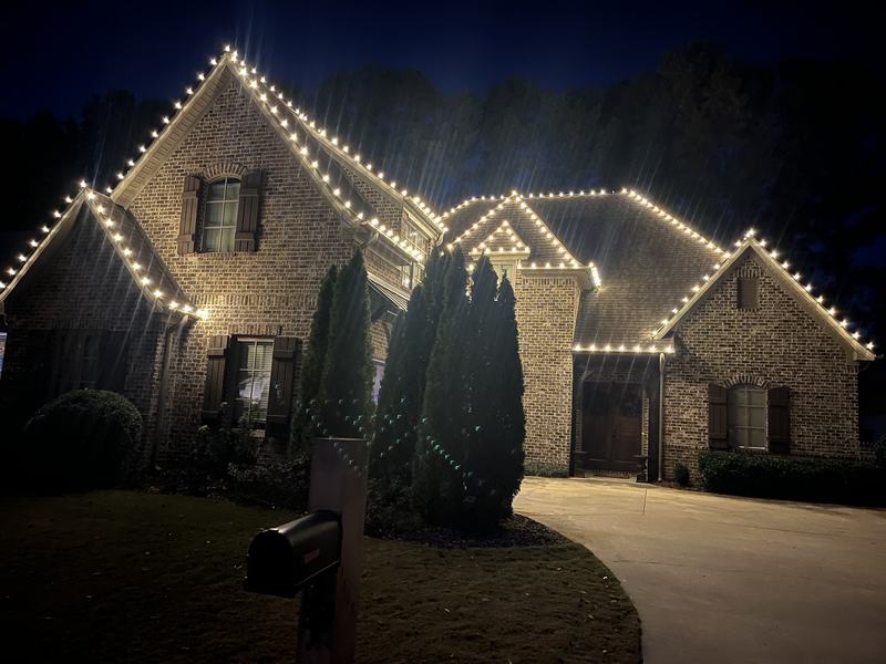 Permanent Outdoor Lighting (Color-Changing Trim) project — Brick house C9 roofline framed by arborvitaes