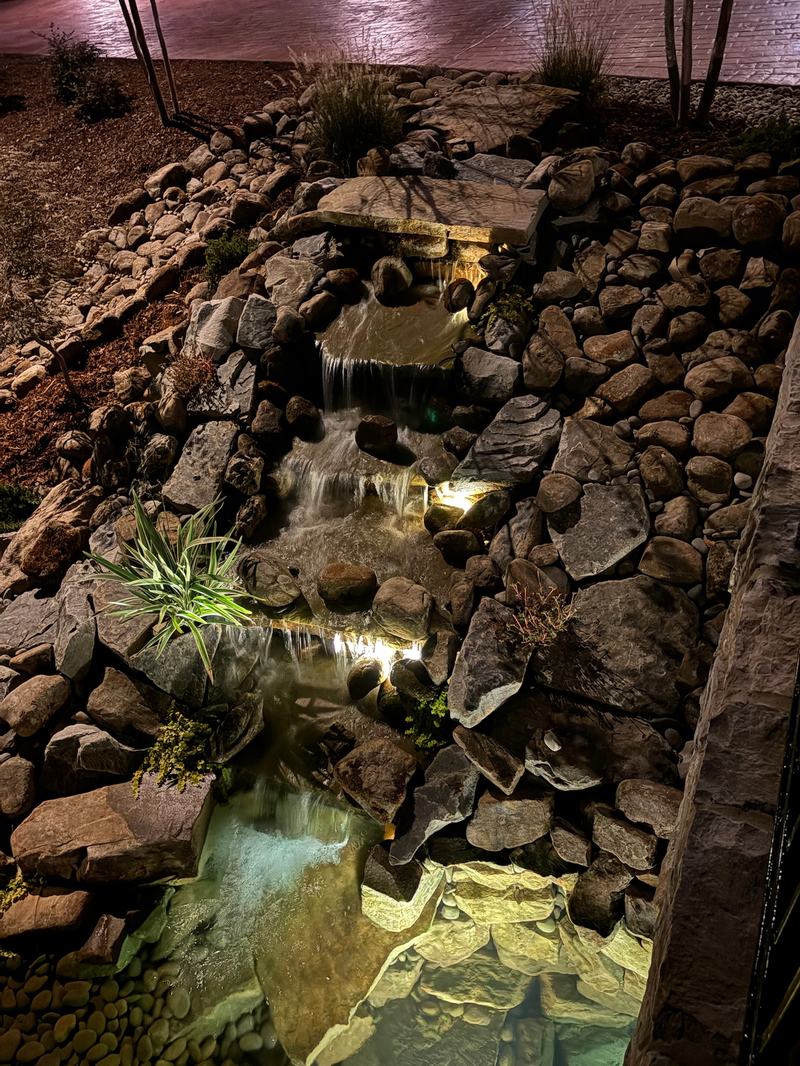 Patio, Pool & Backyard Lighting project — Rock waterfall water feature lit within stones