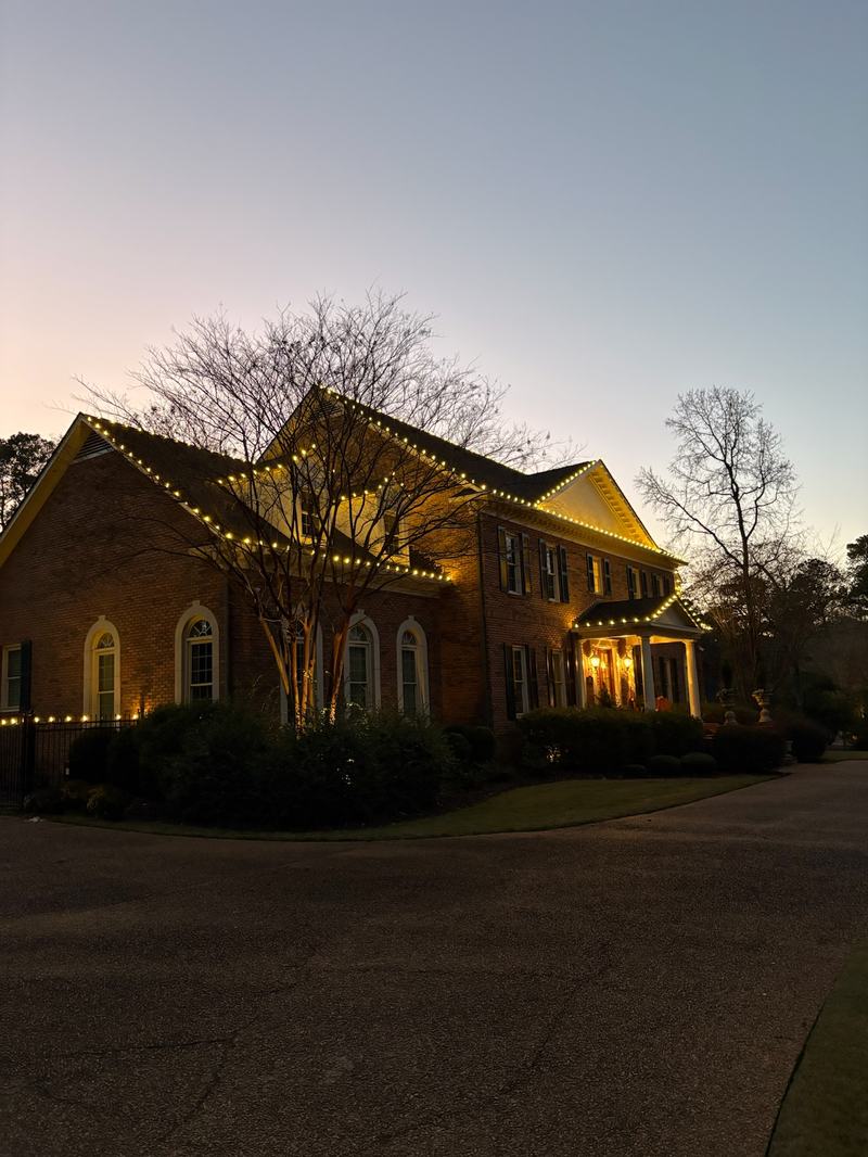 Permanent Outdoor Lighting (Color-Changing Trim) project — Brick two-story C9 roofline against sunset sky
