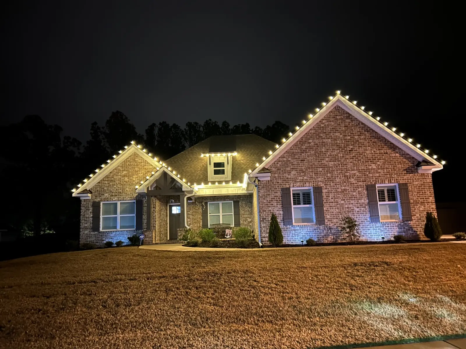 Brick ranch home with warm white C9 Christmas lights along the roofline